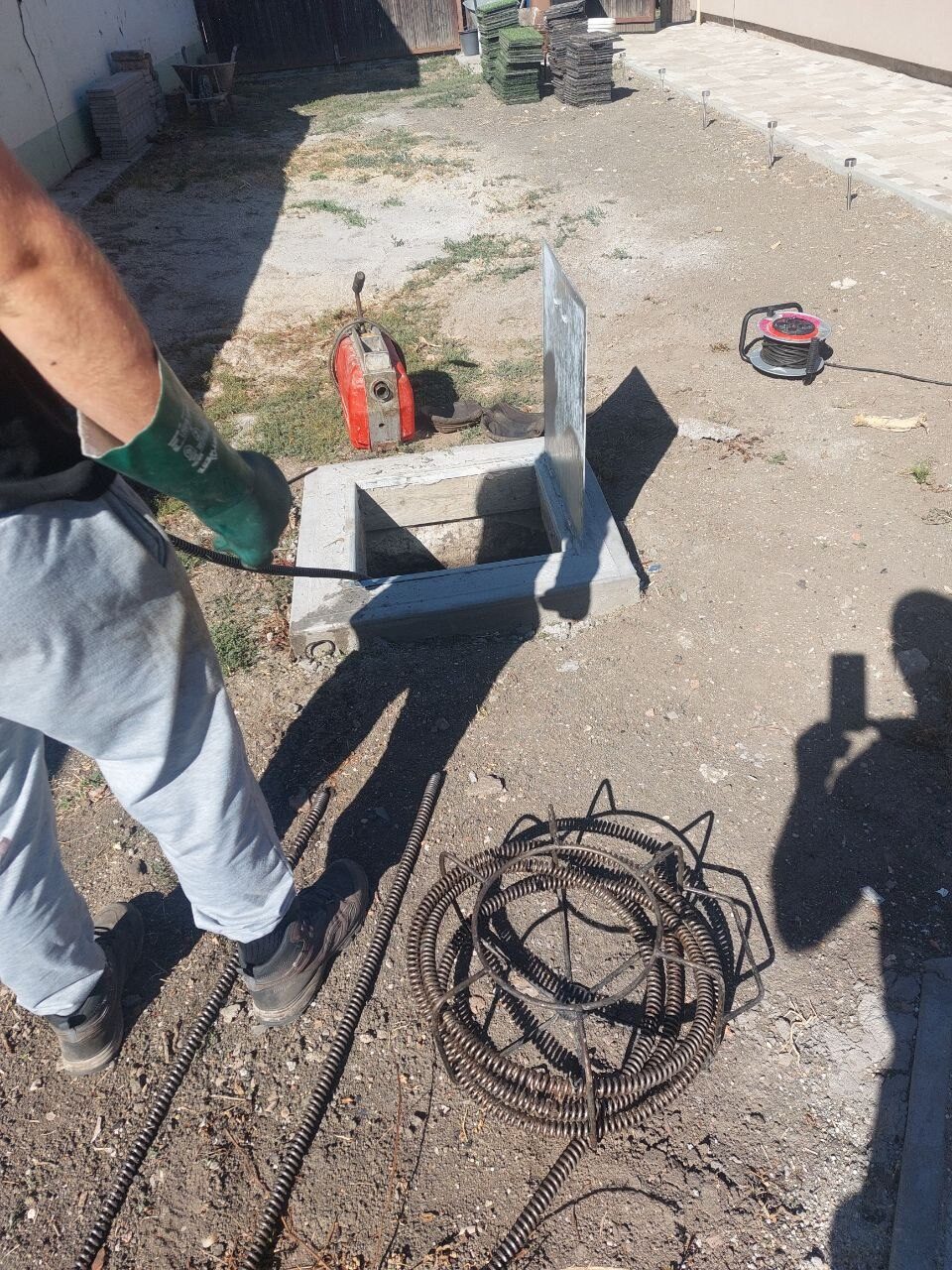 Gép és spirál az udvaron, a nyitott akna mellett